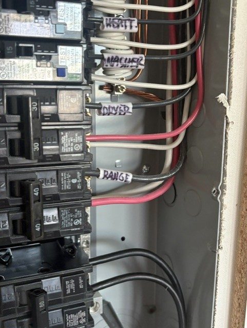 Close-up of hand-labeled circuit wiring for washer, dryer, and range